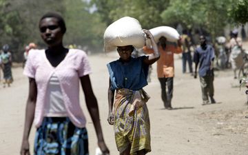 Mensen dragen witte zakken voedsel op hun hoofd