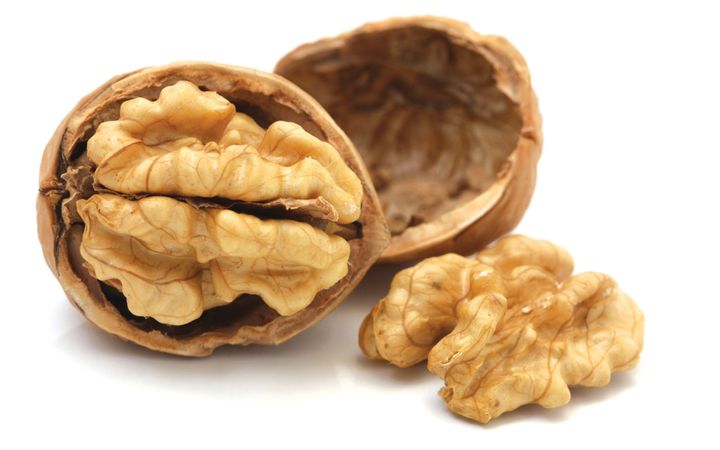 Een walnoot in twee helften. In de linkerhelft zit de noot nog; de rechterhelft is leeg, de noot ligt ernaast.