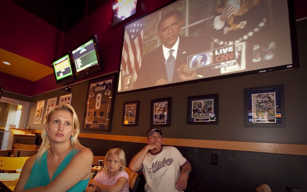 Stacy Jenkins, Alexis Whitney (7) and Mark Whitney (r.) volgen de toespraak van de Amerikaanse president Obama in Buffalo Wild Wings in Houma, in de staat Louisiana. Foto EPA