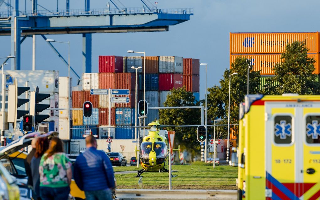 Havengebied met containers en portaalkranen; met op de voorgrond een traumahelicopter en een ambulance.