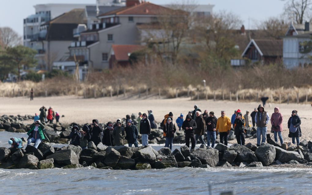 Een groep mensen staand op basaltblokken langs de kust.