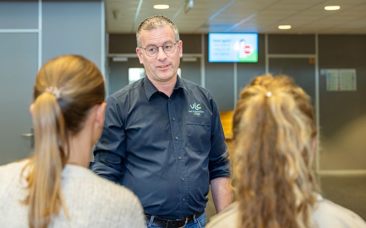 Conciërge in gesprek met twee vrouwelijke leerlingen. 