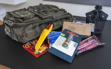 Een groene tas, een zaklamp, radiootje, veldfles en losse attributen.