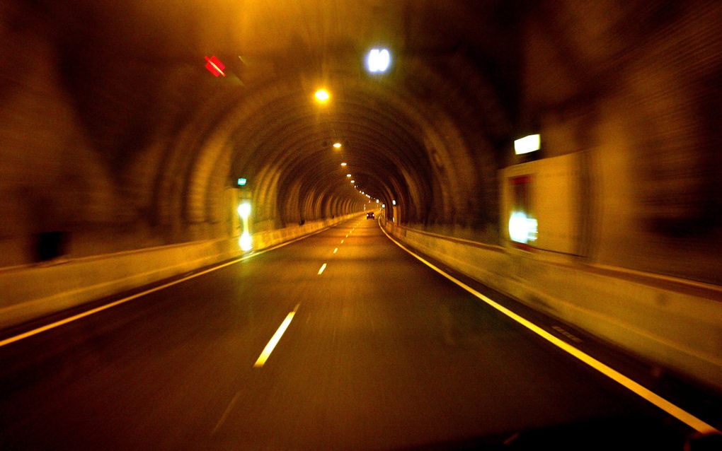 De Westerscheldetunnel, die Zeeuws-Vlaanderen en Zuid-Beveland met elkaar verbindt. beeld Sjaak Verboom
Tunnelbuis met in de verte een auto, in geeloranje licht.