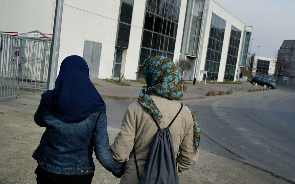 Twee vrouwen op straat, ze dragen elk een hoofddoek. 