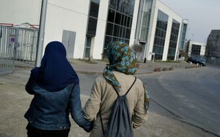 Twee vrouwen op straat, ze dragen elk een hoofddoek. 