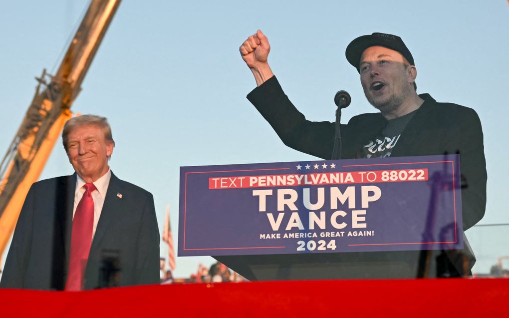 Donald Trump en Elon Musk staan op het podium tijdens een rally. beeld AFP, Jim Watson