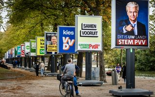 Borden met daarop verkiezingsaffiches van diverse politieke partijen. Op de voorgrond lopen mensen.