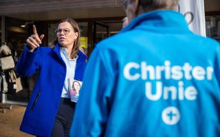Vrouw in blauwe jas met op de voorgrond een man in een lichtblauwe jas van de ChristenUnie.
