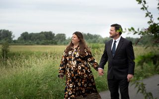 Een echtpaar wandelt op een fietspad en kijkt naar het grasland naast het pad.