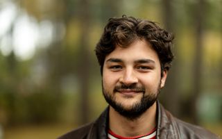 Portretfoto van een man met bruin haar, baardje en neusringetje. 