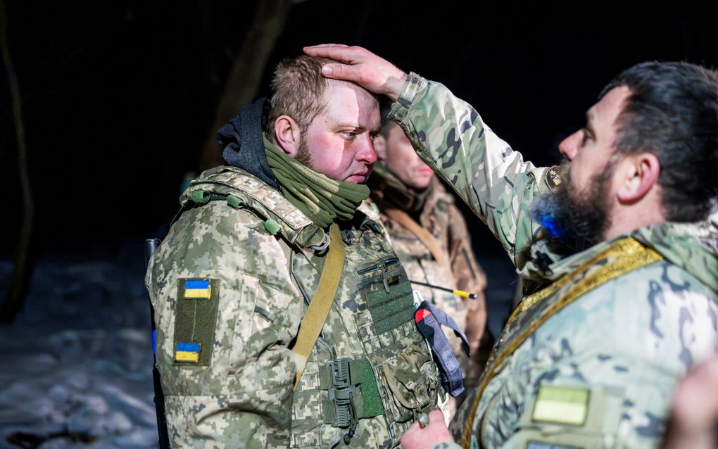 Kapelaan Yoeri zegent een Oekraïense militair in een trainingskamp nabij het front in Shevchenkove. beeld Cees van der Wal