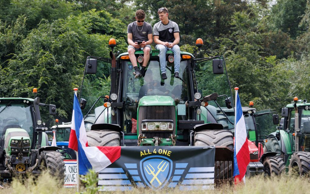 Twee Nederlandse boeren zitten op een trekker in het Atomiumpark in Brussel. Het groots aangekondigde Europese boerenprotest, voorafgaand aan de Europese verkiezingen, trok volgens de politie zo’n vijfhonderd deelnemers. beeld AFP, Simon Wohlfahrt. 