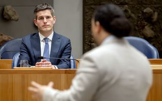 man in blauw pak wordt toegesproken door man in wit pak