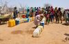 Sudanese vrouwen en kinderen staan in het vluchtelingenkamp Farchana in Tsjaad in de rij om water te halen. beeld AFP, Joris Bolomey