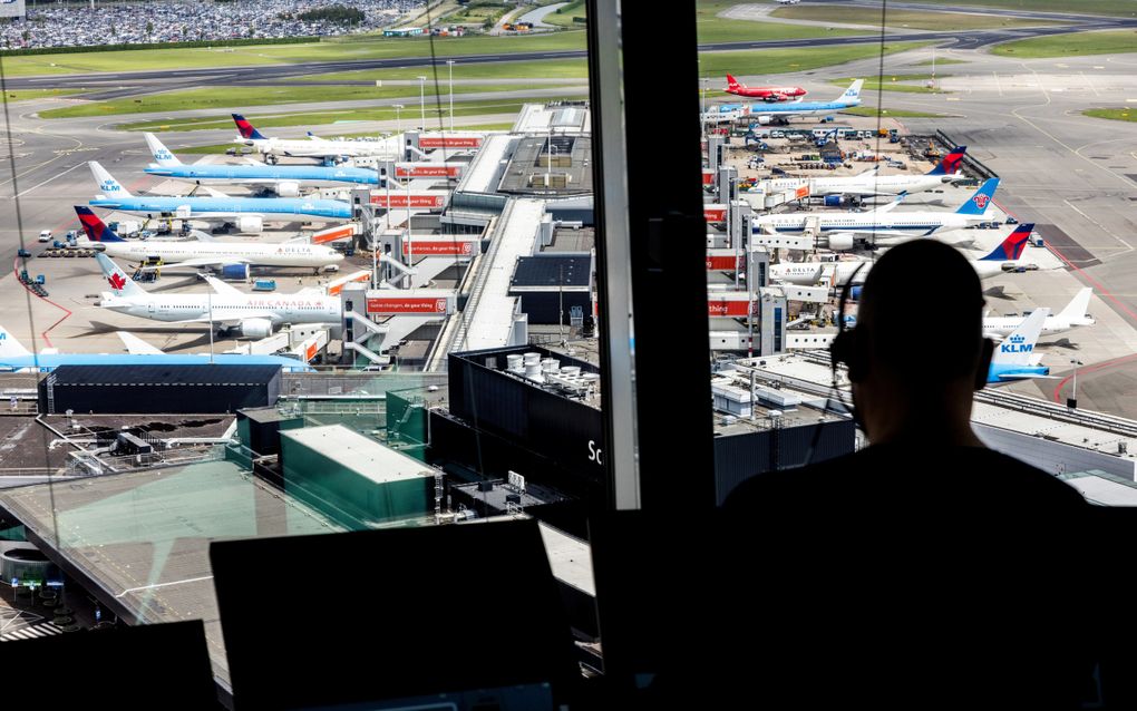 Vliegtuigen staan bij de gate van luchthaven Schiphol, gezien vanuit de verkeerstoren. Schiphol maakte deze week bekend dat een nieuwe pier in april 2027 in gebruik genomen wordt. Dat is acht jaar later dan aanvankelijk verwacht. beeld ANP, Jeffrey Groeneweg.