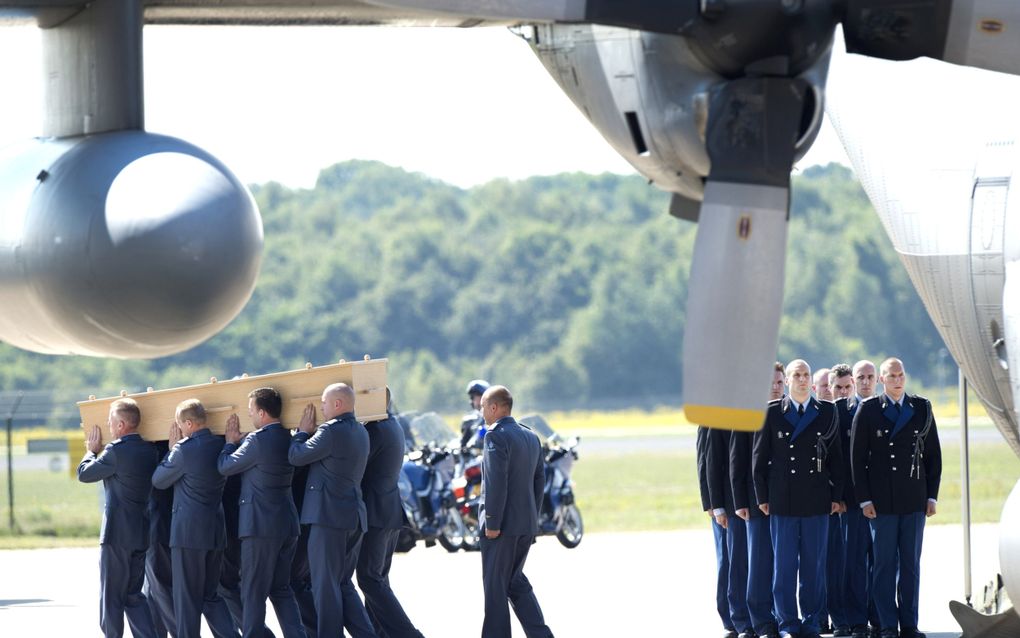 Militairen dragen in juli 2014 op Vliegbasis Eindhoven een kist met een van de slachtoffers van de MH17-ramp. beeld ANP, Marcel van Hoorn