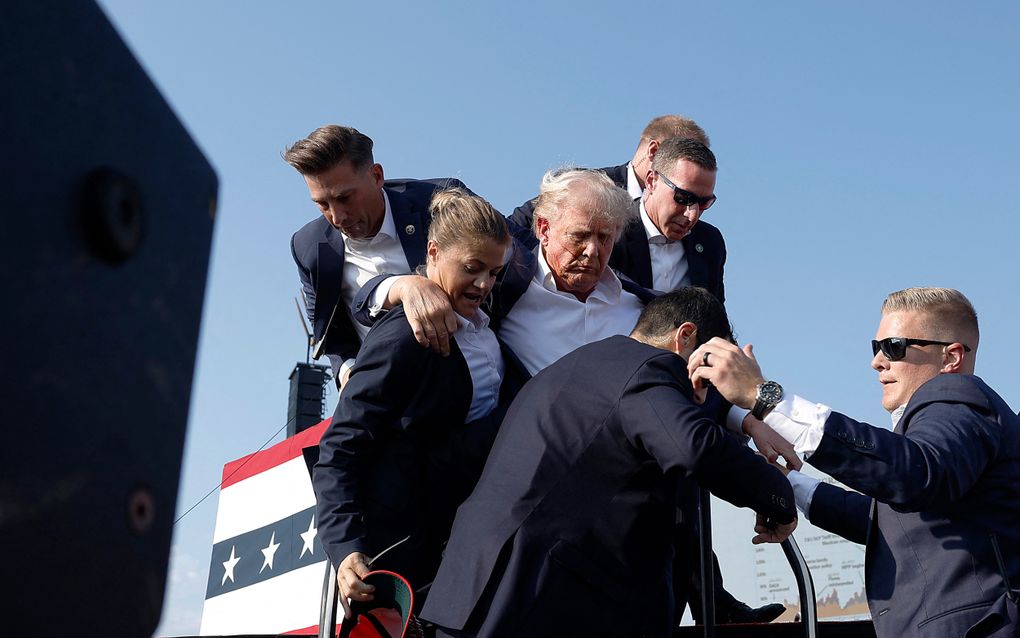 Een gewonde Donald Trump wordt zaterdag door beveiligingsmensen afgevoerd van het podium in Butler, Pennsylvania. beeld AFP, Anna Moneymaker