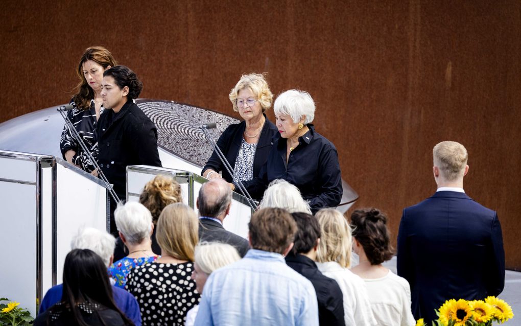 Nabestaanden staan in de rij om de namen en leeftijden van de slachtoffers voor te lezen tijdens de herdenking van rampvlucht MH17. Op de achtergrond het gedenkteken waarop de namen staan. beeld ANP, Robin van Lonkhuijsen