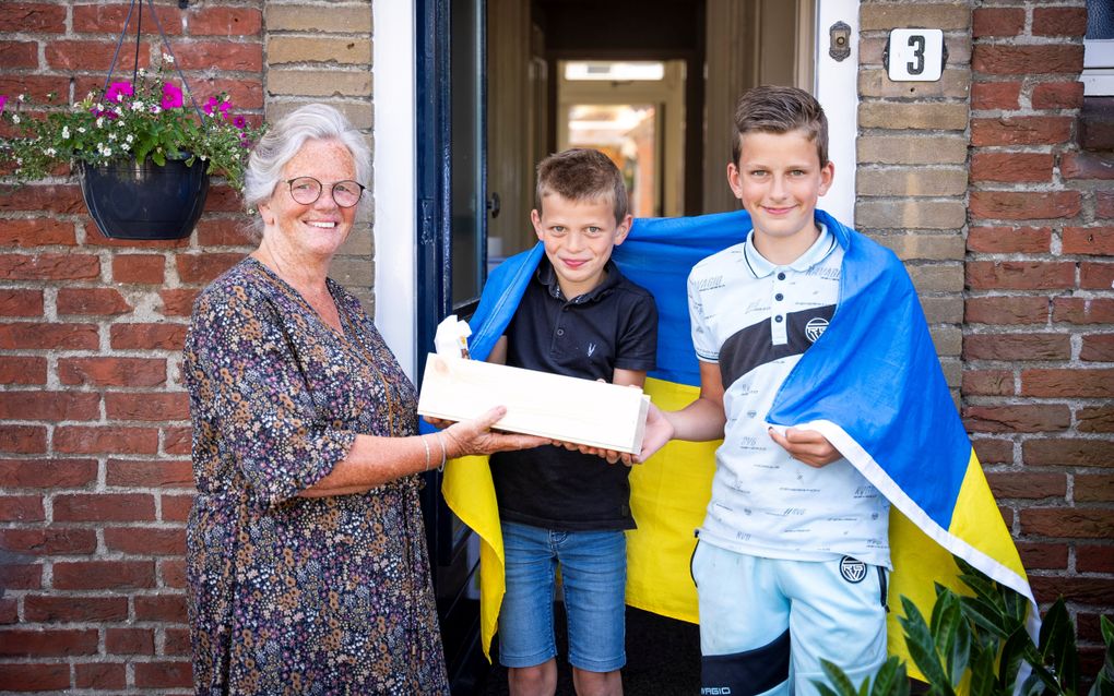 Oma Alma de Wildt geeft haar twee kleinzoons Lauwrenz (l.) en Peter (r.) een notenpakket. „Ik vind het bijzonder dat ze zich op deze jonge leeftijd inzetten voor anderen.” beeld Cees van der Wal