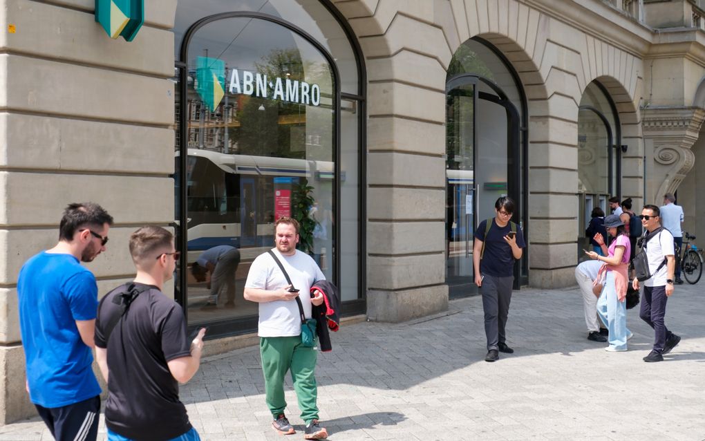 Mensen passeren in juli het gebouw van ABN AMRO in Amsterdam. De bank bestaat tweehonderd jaar in 2024 en wil tegenwoordig vooral de samenleving dienen met vermogen. beeld ANP/Hollandse Hoogte, Kim van Dam