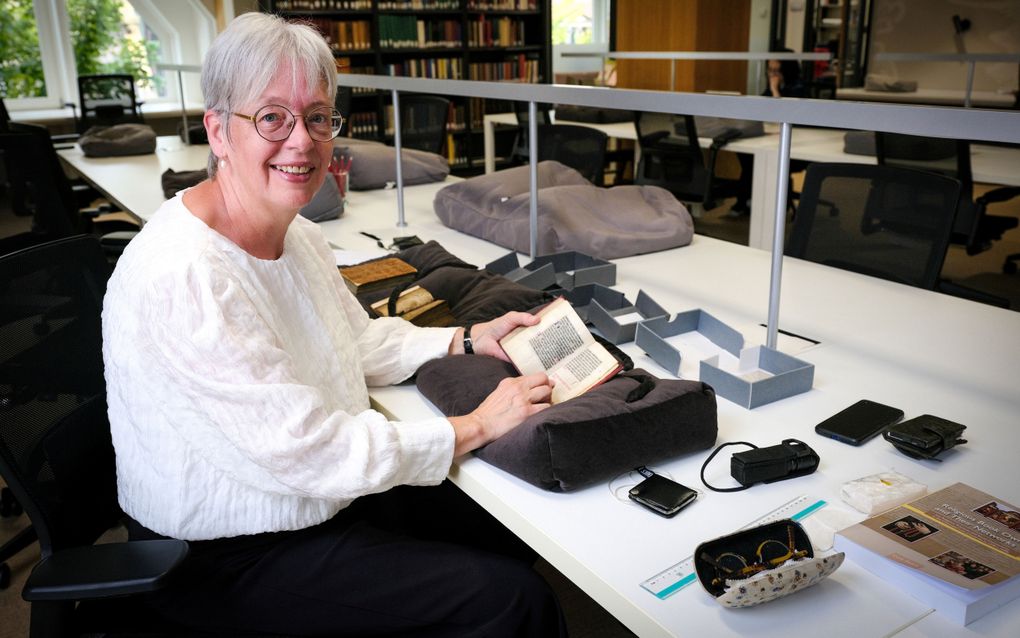 Dr. Cora Zwart met een van de boeken die ze onderzocht. beeld Jan Willem van Vliet