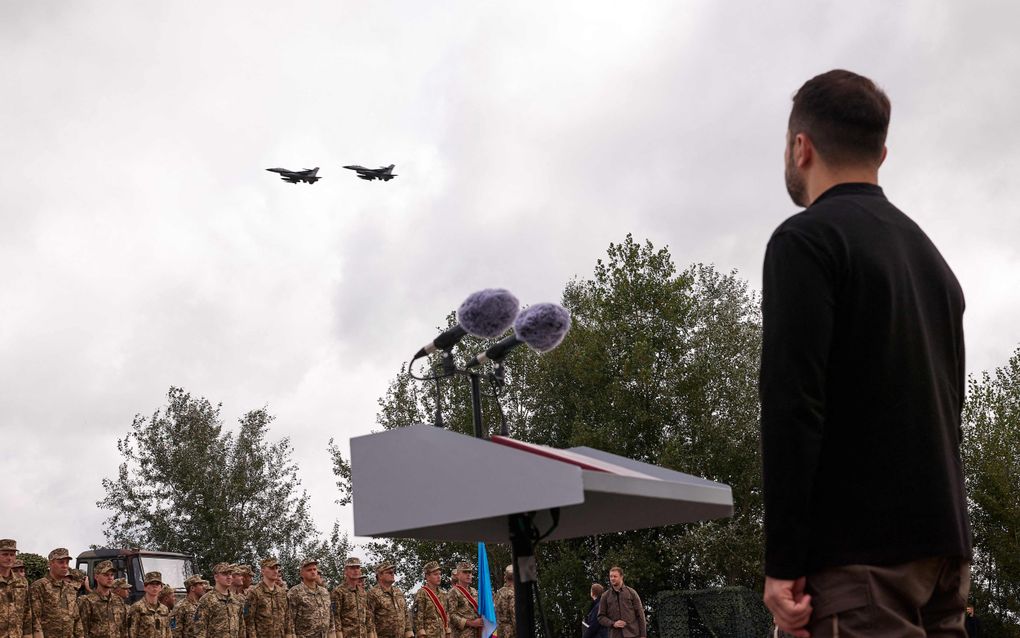 Zelensky kijkt naar twee F16’s die overvliegen, terwijl hij een toespraak houdt in Kiev. beeld AFP/UKRAINIAN PRESIDENTIAL PRESS SERVICE