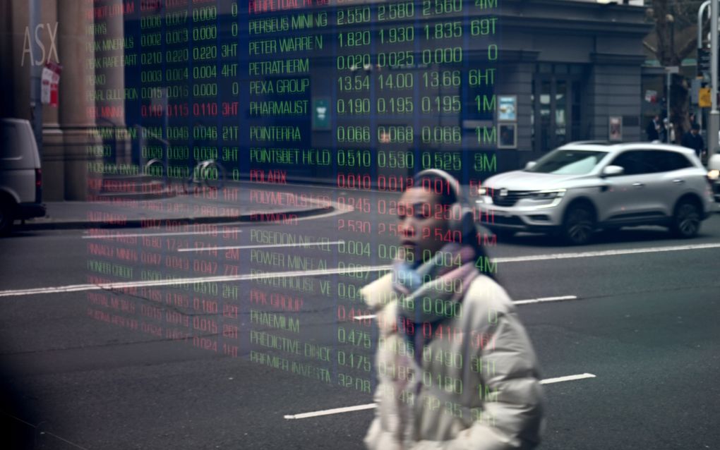 Een voetganger loopt langs een bord van de Australische ASX-index, die ook omlaag ging door recessievrees in de Verenigde Staten. beeld EPA, Bianca de Marchi