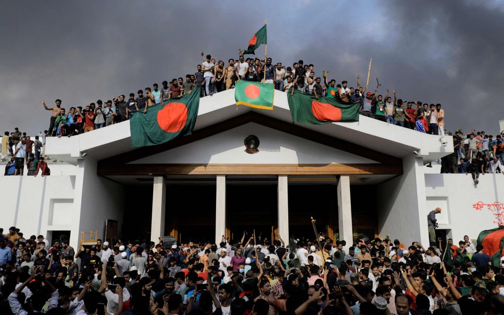 Antiregeringsdemonstranten staan maandag op het dak van de ambtswoning van premier Sjeika Hasina Wajed in de Bengalese hoofdstad Dhaka. De premier is afgetreden en het land ontvlucht. beeld AFP, K.M. Asad