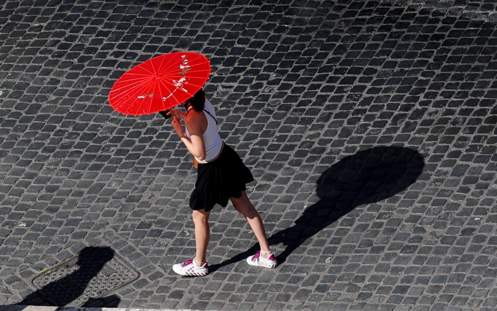 Een vrouw in Rome draagt een parasolletje om zich te beschermen tegen de hitte van de zon. Vorige week bereikten de temperaturen in de Italiaanse hoofdstad de 40 graden. beeld EPA, Giuseppe Lami