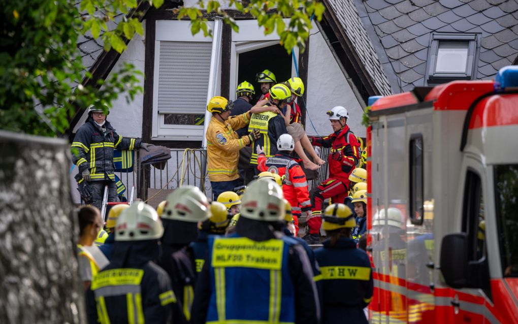 Reddingswerkers tillen een vrouw naar buiten bij het ingestorte hotel in het Duitse Kröv. beeld AFP 