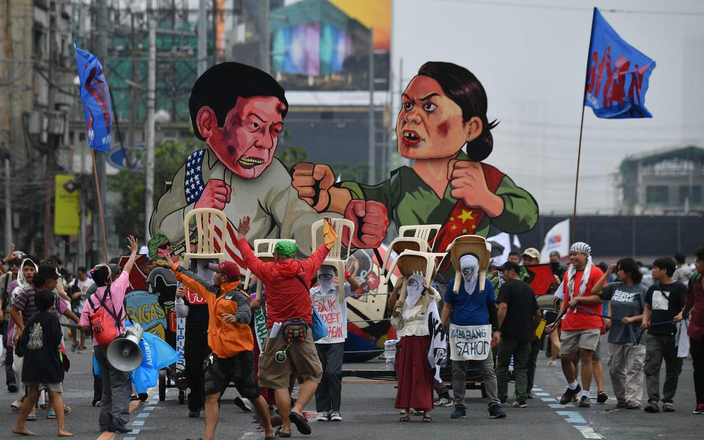 Betogers in Manila met afbeeldingen van president Ferdinand Marcos jr. en vicepresident Sara Duterte. beeld AFP, Ted Aljibe