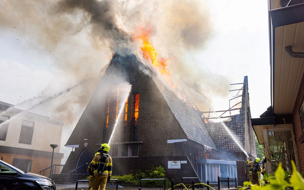 De kerk in vlammen. Links het appartement dat uit voorzorg natgehouden wordt. Recht het huis waar de bewoners van geëvacueerd moesten worden met een twee weken oude baby. beeld Stefan Verkerk 