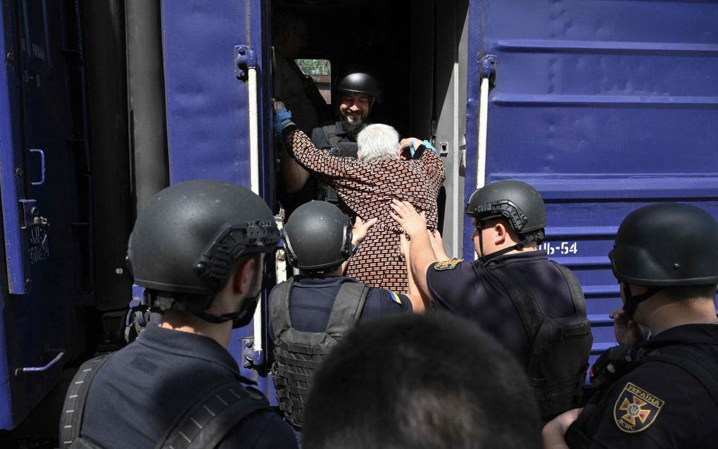 Officials helpen woensdag een oudere vrouw aan boord te gaan van een evacuatietrein op een onbekende locatie in de regio Donetsk. beeld AFP, Genya Savilov 