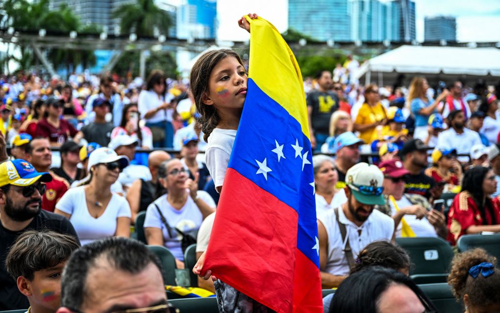 Een meisje houdt de nationale vlag van Venezuela vast tijdens een demonstratie tegen de vermeende verkiezingsfraude van de zittende president Nicolas Maduro. (Photo by CHANDAN KHANNA / AFP)