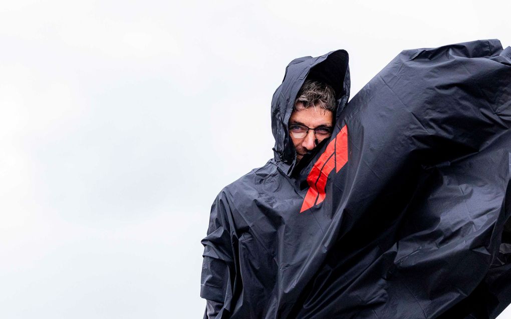 beeld ANP, Ramon van Flymen
Man in zwarte regencape.  
