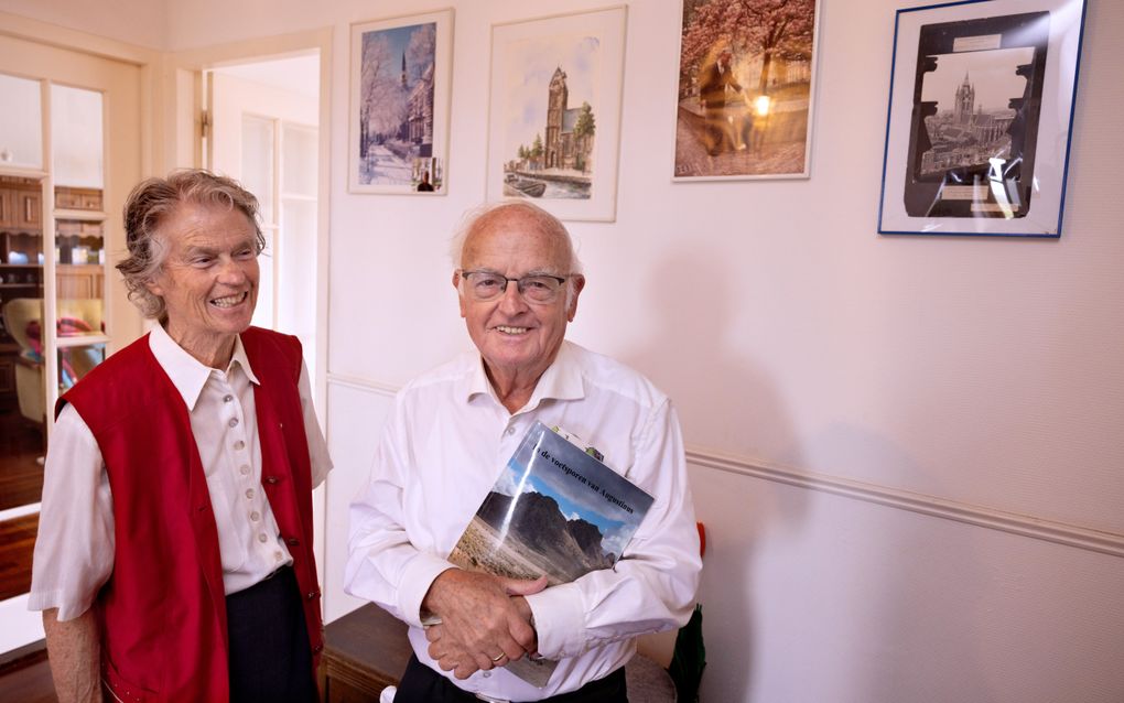 Ds. C. Blenk en zijn echtgenote in de hal van hun Haagse flat. Aan de wand hangen vier foto’s van de plaatsen waar ds. Blenk als predikant een gemeente heeft gediend. beeld Dirk Hol