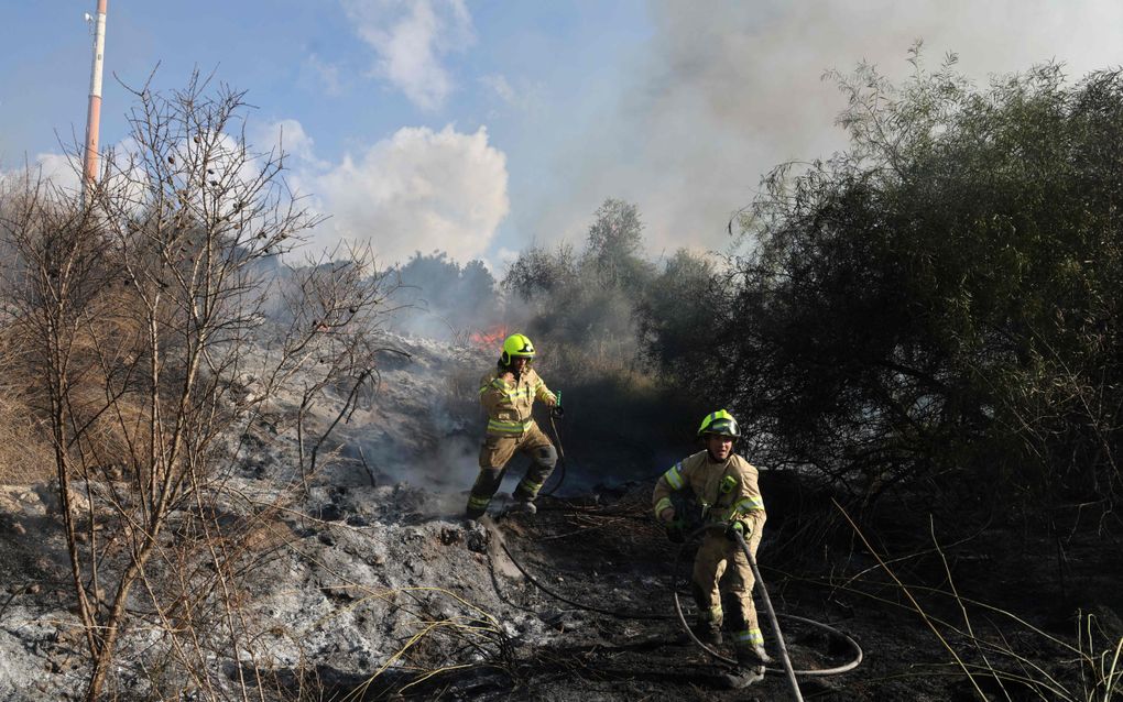 Israëlische brandweerlieden blussen de brand die is ontstaan na het neerkomen van de resten van een ballistische raket die door Jemenitische Houthirebellen is afgevuurd. beeld AFP, Menahem Kahana