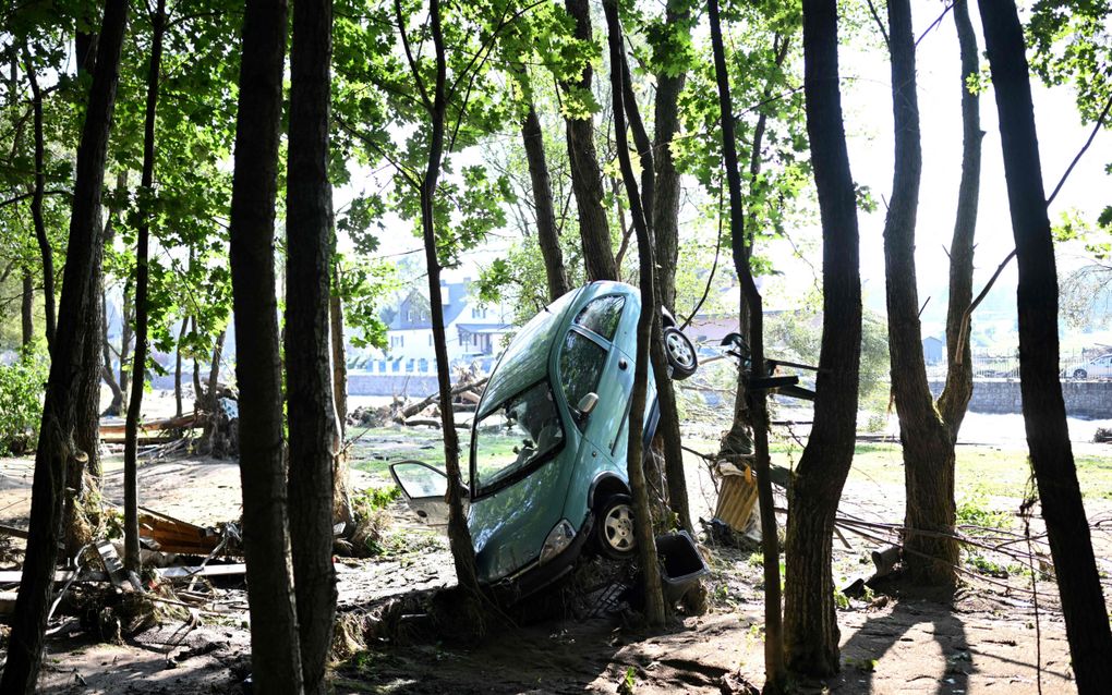 Het wassende water heeft een auto opgetild en rechtop tussen de bomen geparkeerd in de buurt van een rivier in Zuid-Polen. beeld AFP, Sergei Gapon