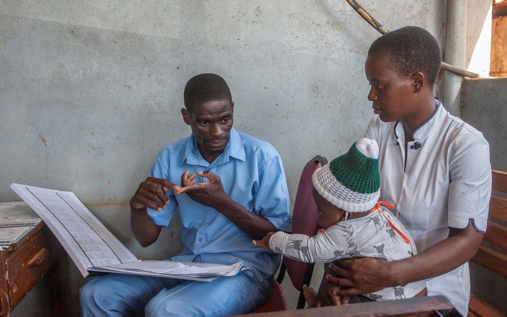 Een verpleegkundige in gesprek met moeder en kind in Malawi. beeld AFP, Amos Gumulira