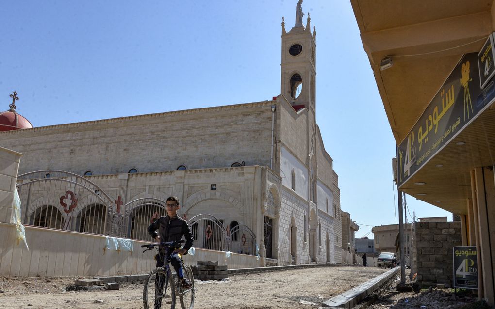 Een jongen staat bij een Syrisch-katholieke kerk in de overwegend christelijke stad Qaraqosh, in de provincie Ninevé. Veel christenen zien er geen toekomst meer. beeld AFP, Zaid Al-Obeidi