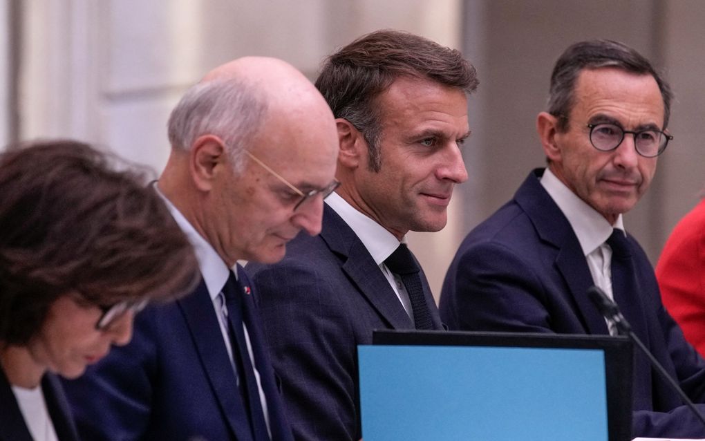 De Franse president Emmanuel Macron wordt tijdens de wekelijkse vergadering van de ministerraad geflankeerd door minister van Justitie Didier Migaud (l.) en minister van Binnenlandse Zaken Bruno Retailleau. beeld AFP, Christophe Ena 