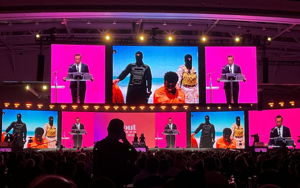 Patrick Fung spreekt woensdag op het wereldevangelisatiecongres in Incheon in Zuid-Korea. Op het scherm een foto van de 21 christelijke martelaren die in 2015 op een strand in Libië door Islamitische Staat werden gedood. beeld RD