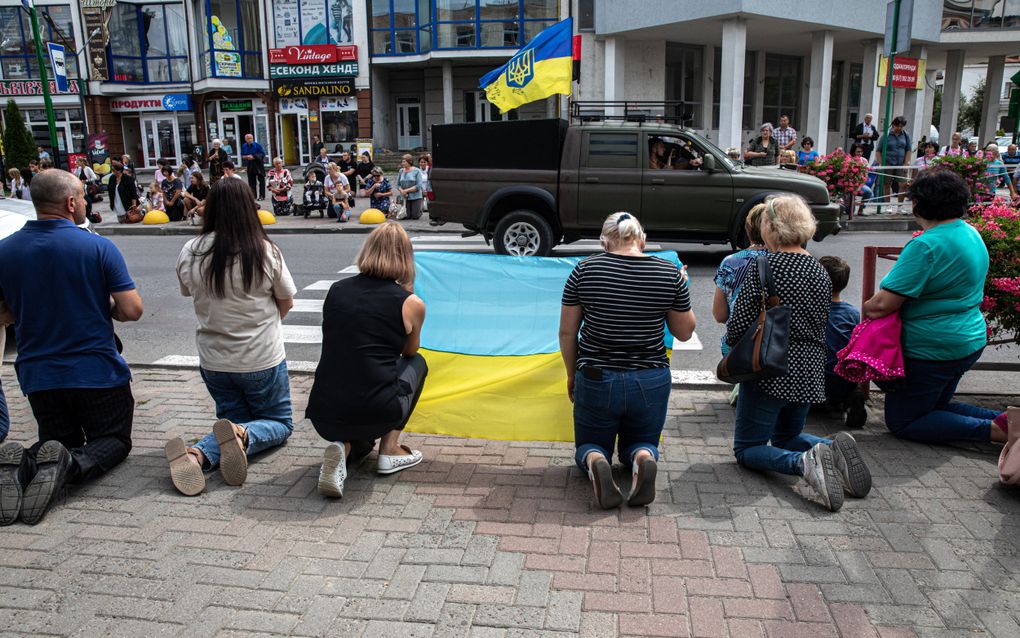 Inwoners van het plaatsje Nadvirna knielen langs de weg als eerbetoon aan een Oekraïense soldaat die aan het front werd gedood. beeld Kostyantyn Chernichkin