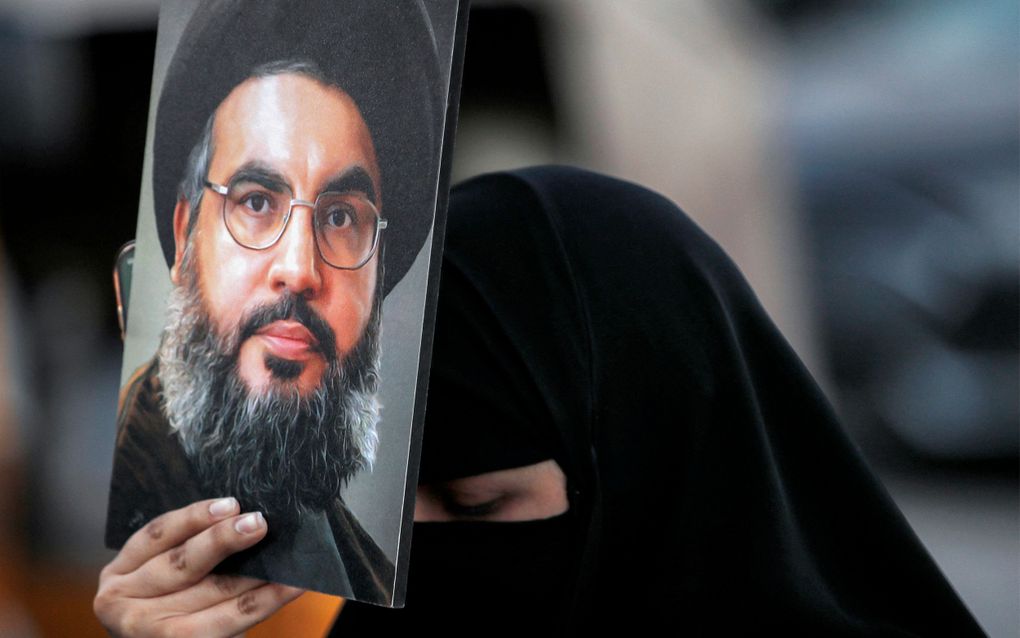 Een gesluierde vrouw toont een tekening van Hezbollahleider Hassan Nasrallah, die vrijdag bij een Israëlische luchtaanval is gedood. beeld AFP, Ahmad Al-Rubaye