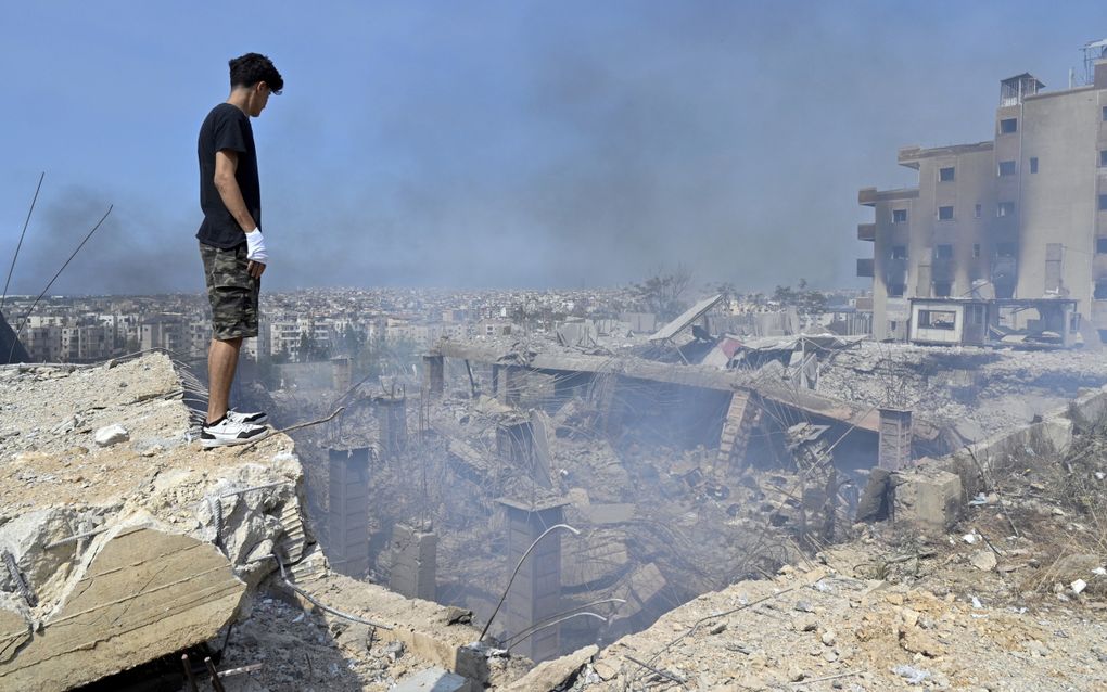 Een Libanees kijkt naar de krater die is ontstaan na een Israëlische luchtaanval op Beiroet. beeld EPA, Wael Hamzeh