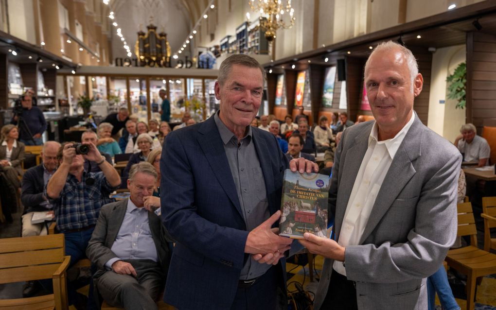 Vertaler Frank De Roo (r.) en redacteur Leendert Torn met de nieuwe uitgave van ”De imitatie van Christus” in boekhandel Van der Velde in Zwolle. beeld Freddy Schinkel