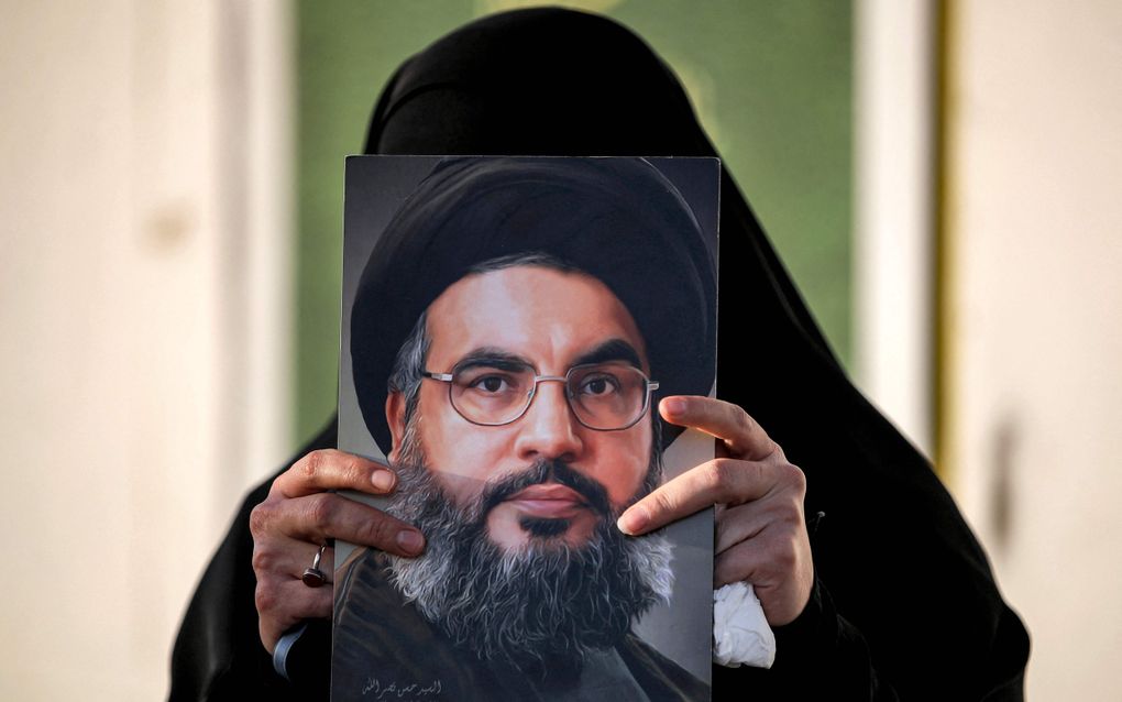 Een vrouw houdt een schilderijtje van de overleden Hezbollahleider Hassan Nasrallah omhoog. beeld AFP, Ahmad Al-Rubaye