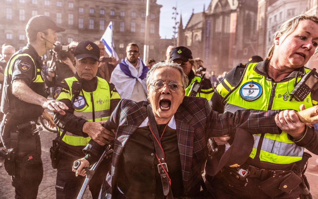 De politie pakt een tegendemonstrant op tijdens de herdenkingsbijeenkomst op de Dam voor de brute terreuraanval van Hamas op Israël, maandag een jaar geleden. beeld ANP, Eva Plevier