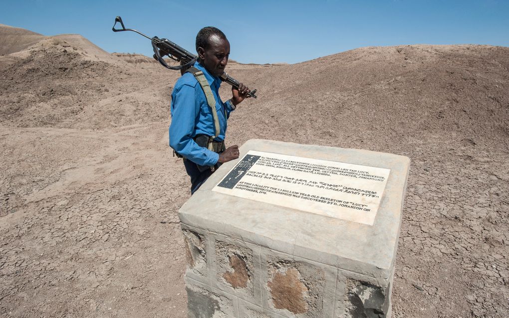 Een Ethiopische politieagent legt zijn hand op het monument dat de vindplaats markeert van het fossiel van Lucy. Het oorspronkelijke fossiel van Lucy wordt bewaard in het Nationaal Museum van Ethiopië in Addis Abeba. beeld iStock